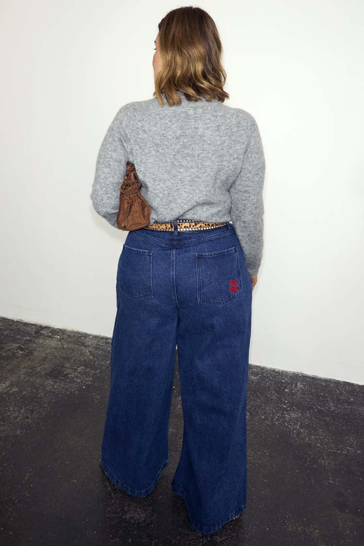 Blue Denim Pallazzo Jan Jean with a wide leg and red pocket embroidery, shown from behind for inclusive sizing.