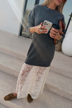 Grey Knit Jumper Dress with a sheer white lace skirt, styled with brown loafers and a coffee on stone steps.