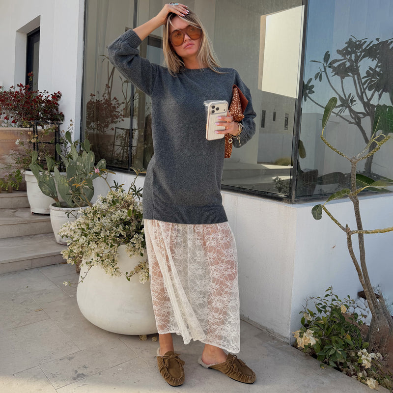 Grey knit jumper dress with a delicate white sheer lace skirt, styled with sunglasses for a casual street style look.
