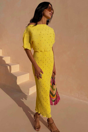 Sunshine Tilly Dress in yellow plissé with gold flecks and lettuce hem, styled with a colourful bag and sunglasses.