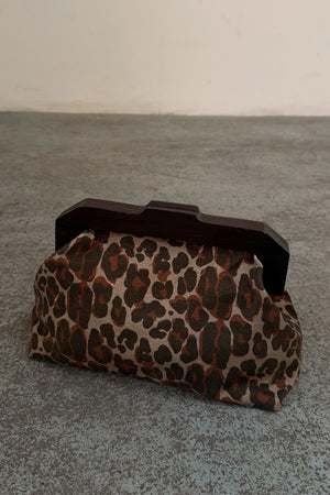 Lucia Leopard Denim Bag with an iconic leopard print and dark wooden handle, shown on a textured grey floor.