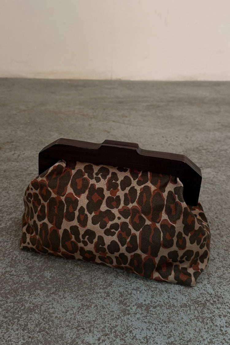 Lucia Leopard Denim Bag with an iconic leopard print and dark wooden handle, shown on a textured grey floor.