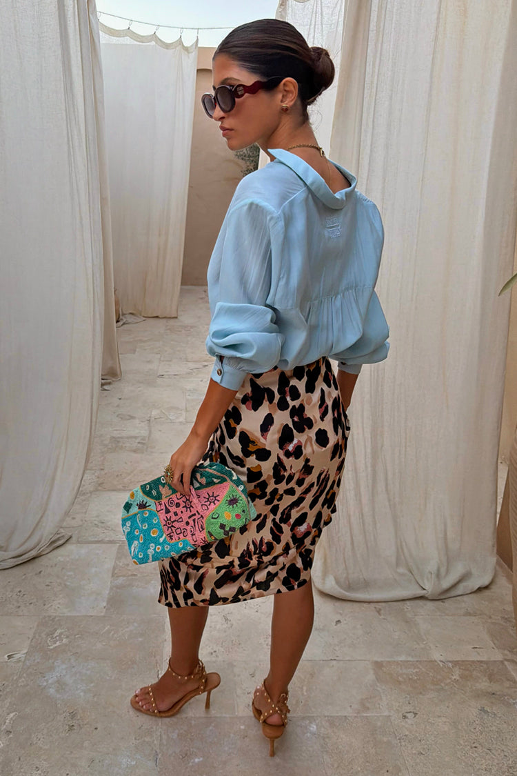 Iconic Brown Leopard Jaspre Skirt in a satin wrap style, paired with a light blue shirt and colourful clutch.
