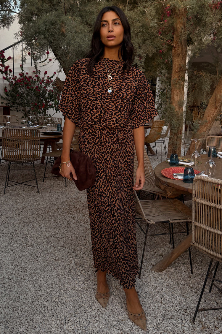 Lucia Leopard Tilly Dress Petite in iconic leopard print plisse fabric, styled with gold jewellery at an outdoor terrace.
