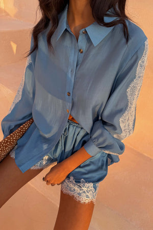 Blue Lace Maeva Shorts in washed blue satin with white lace trim, styled with a matching long-sleeved shirt.