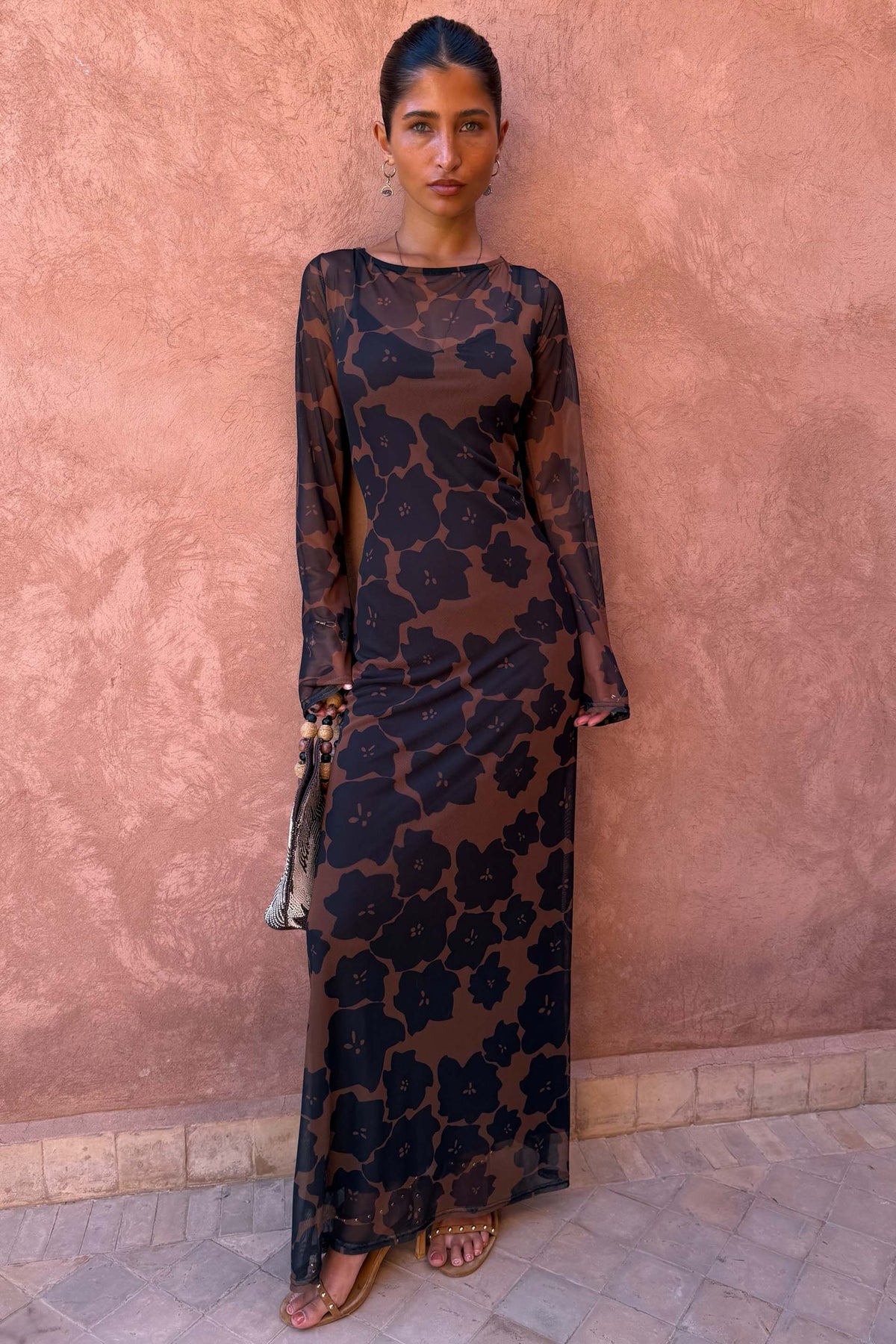 Tan Jaden Floral Mesh Maxi Dress with sheer sleeves and high neck on a model against a pink textured wall.