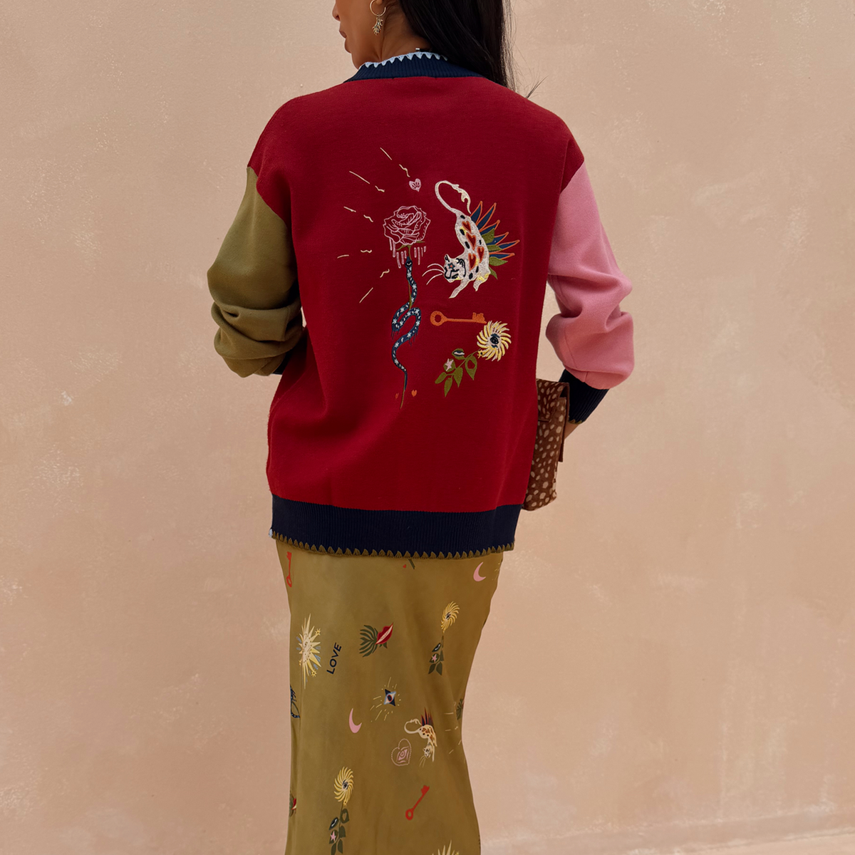 Cardigan Mystical Martha rosso con ricamo mistico sul retro e maniche a contrasto rosa e verde.