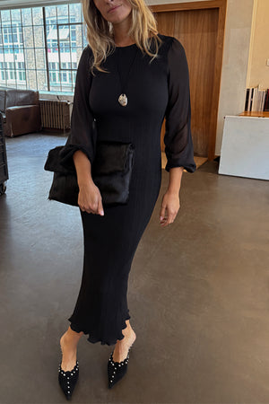 Black Plisse Perrie Dress featuring sheer balloon sleeves and an iconic pleated texture, styled with a clutch.