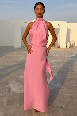 Pink Daphne Skirt in a straight high-waisted fit, styled with a matching halter neck top against white arches.