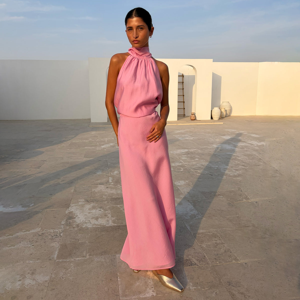 Gonna Pink Daphne rosa in un set coordinato con top accollato e scarpe dorate all'aperto.