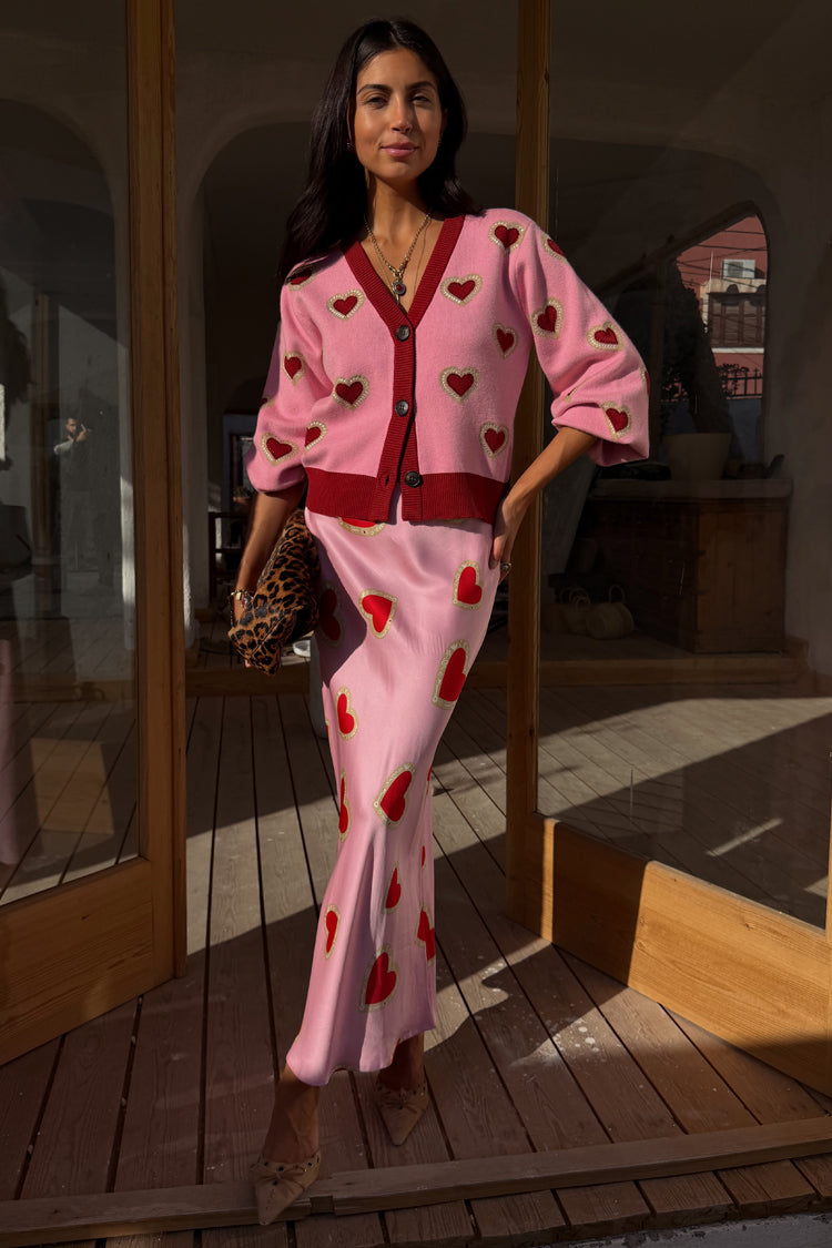 Pink Hearts Dorris midaxi skirt featuring red heart motifs, styled with a matching pink cardigan and leopard clutch.