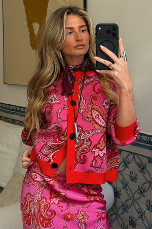 Pink Paisley Oslo Cardigan with red ribbed trims and a boxy fit, styled with a matching skirt in a mirror selfie.