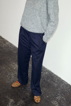 Navy Pinstripe Arden Trousers in a sleek pinstripe print, styled with a grey knit jumper and leopard print shoes.