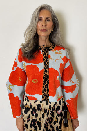 Pale blue Poppy Cardigan with orange floral print and leopard trim, styled with a leopard print skirt.