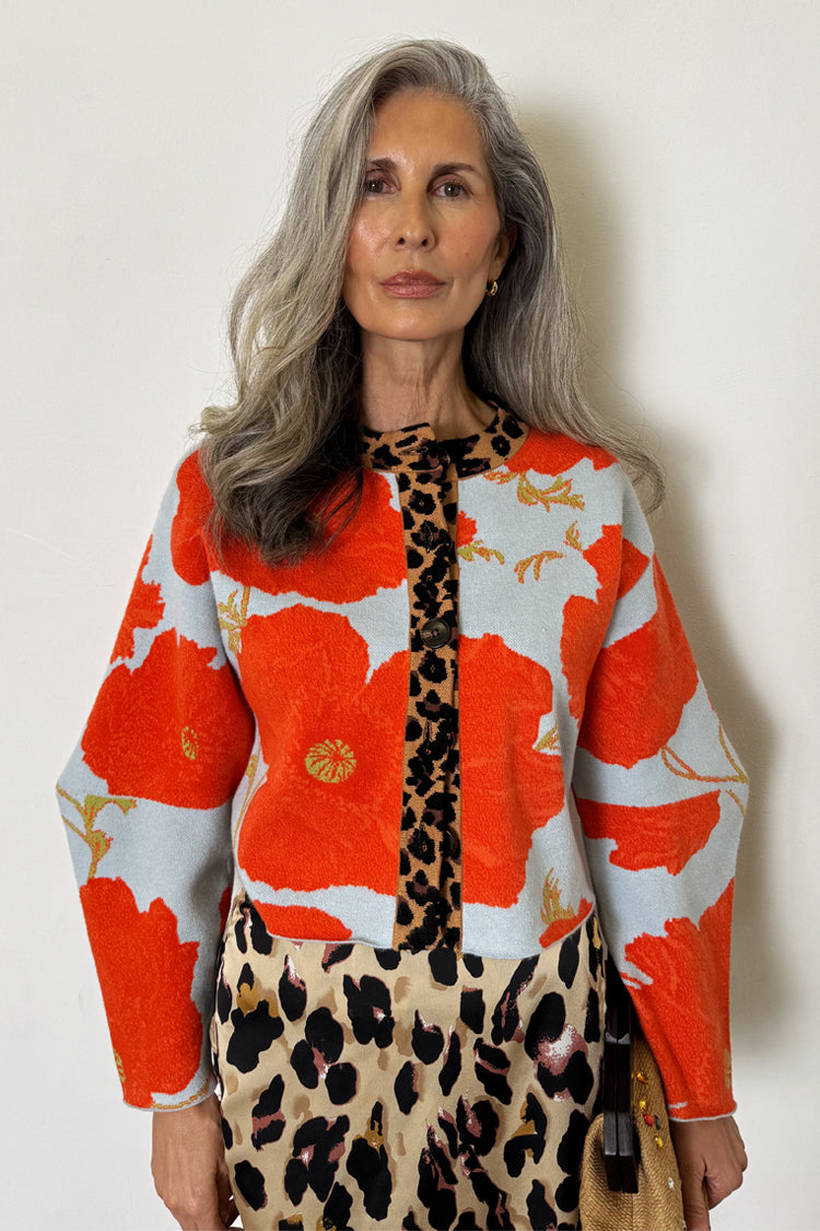 Pale blue Poppy Cardigan with orange floral print and leopard trim, styled with a leopard print skirt.