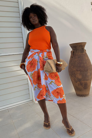 Blue Poppy Jaspre Skirt with orange floral print, styled as a wrap skirt with a bright orange ribbed vest.