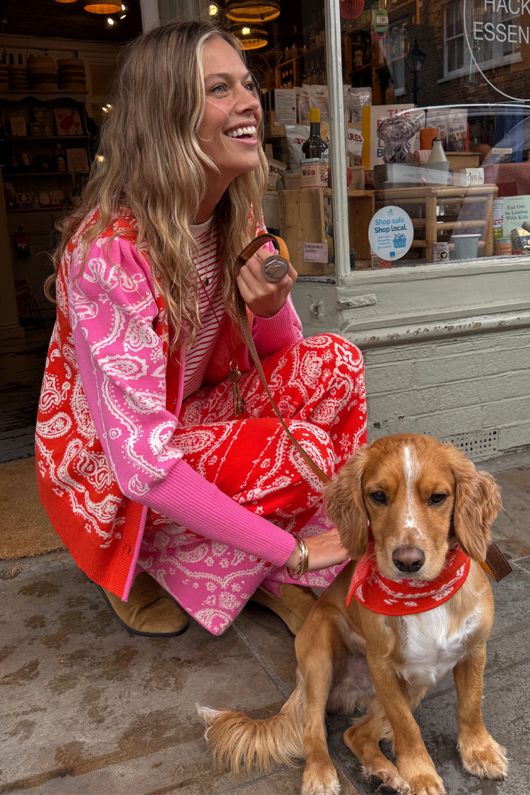 Cardigan Martha con stampa bandana rossa e rosa e pantaloni coordinati, indossati all'aperto con un cane.