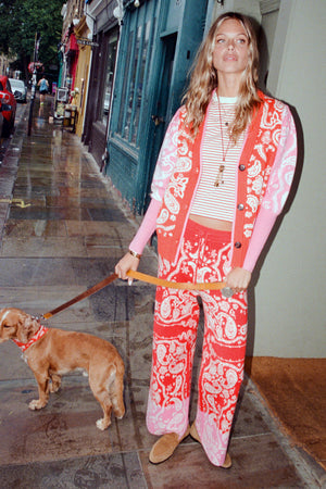 Cardigan Martha rosso e rosa a stampa bandana e pantaloni coordinati indossati in strada con un cane.