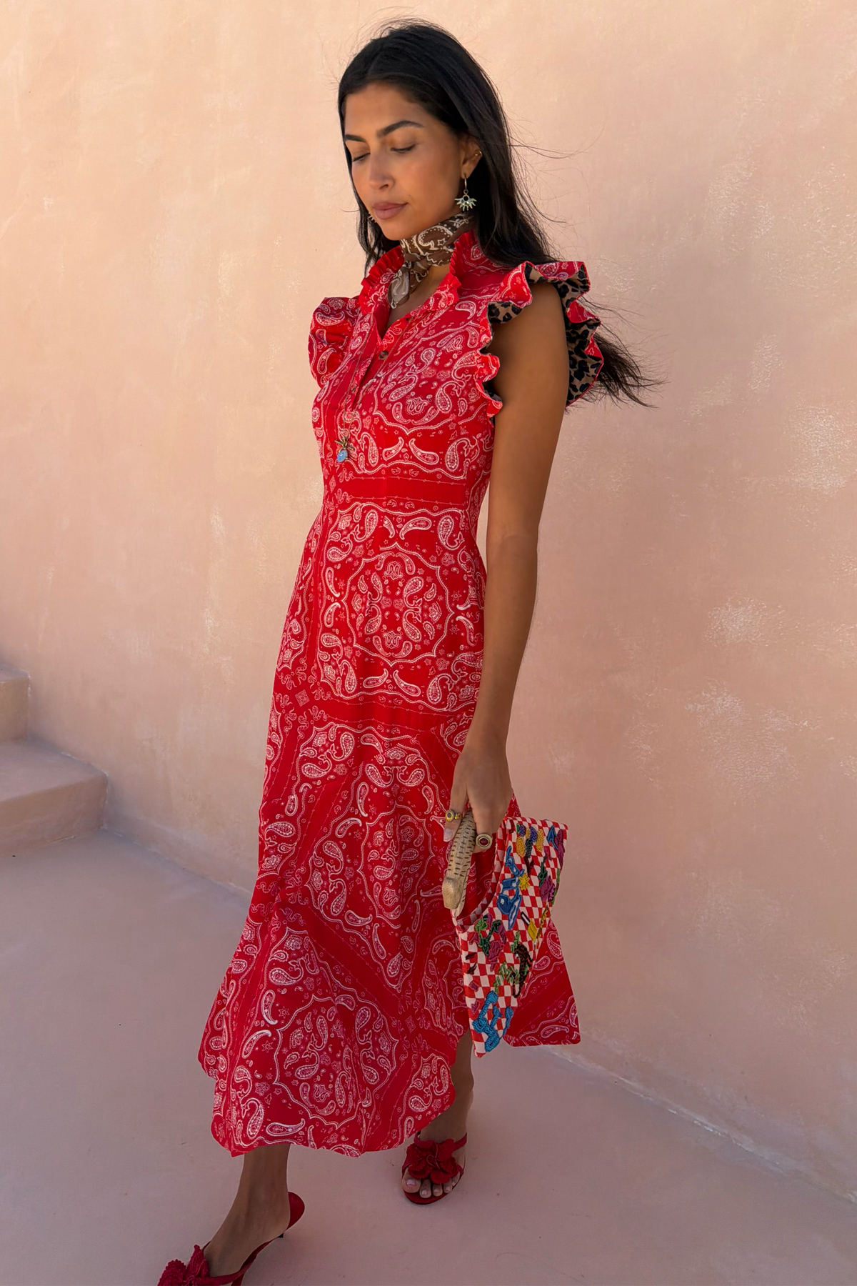 Red Bandana Remi Dress featuring a ruffled neck and leopard print sleeves, styled with a patterned clutch.