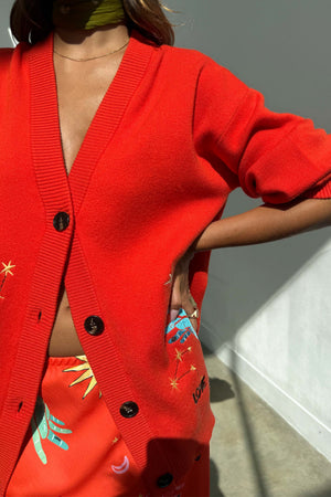 Red Celestial Cardigan in a soft knit with embroidered palm and star motifs, worn with a matching co-ord skirt.