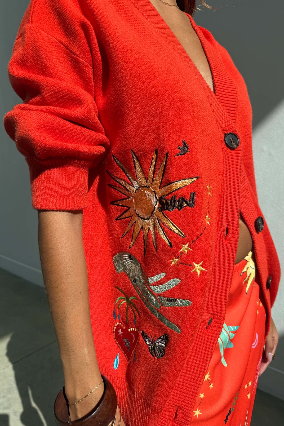 Red Celestial Cardigan featuring embroidered sun, heart and palm motifs on a soft knit with button-up front.