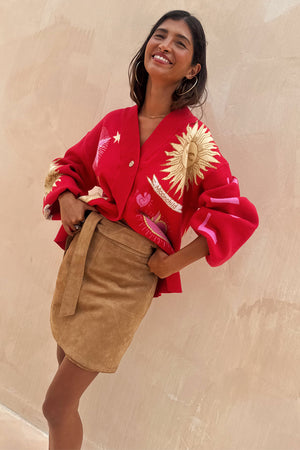 Tan Suede Mini Jaspre wrap skirt on a model styled with a red celestial print cardigan.