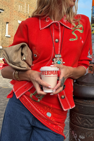 Cardigan mistico rosso con colletto, ricami celestiali e cuciture a contrasto indossato con jeans.