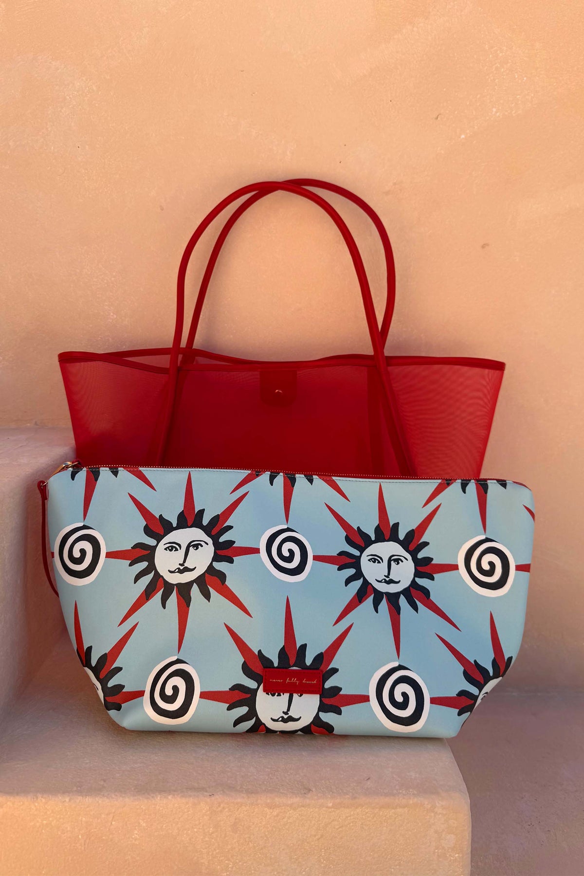 Red Mesh Tote Bag with leather handles and a light blue sun-print pouch on a neutral stone step.