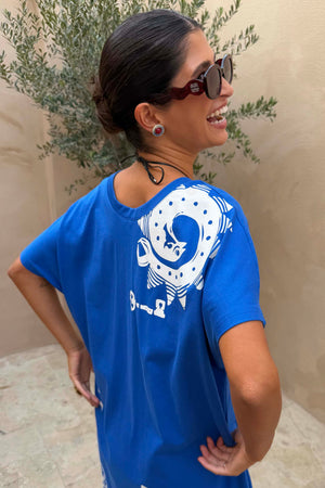 Occhiali da sole rossi Red Wiggle Arm in acetato con stanghette ondulate indossati con t-shirt blu.