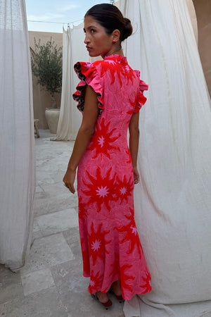 Pink Soleil Remi Dress with red sun motifs, pleated frill sleeves with leopard lining and an asymmetrical skirt.