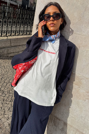 White Rodeo T-Shirt with red text, styled with a pinstripe suit and blue neck scarf for a London look.