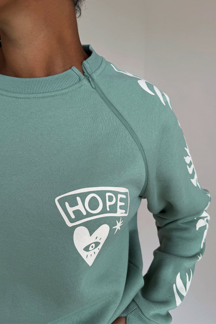 Sage Sundazed Accessible Sweatshirt in green with a cream HOPE graphic and concealed shoulder zip for treatment access.