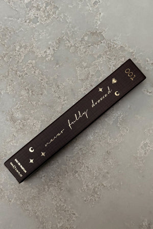 Dark brown NFD Eau De Parfum 001 10ml box with gold foil script and celestial icons on a stone surface.