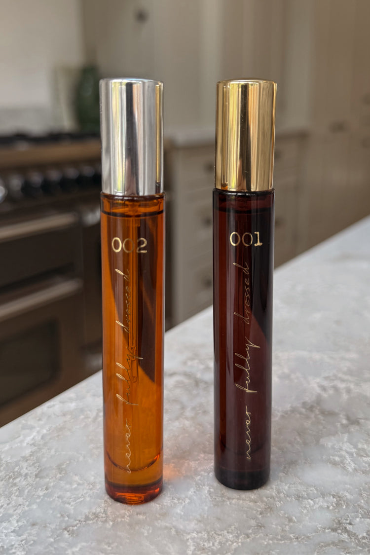 NFD Eau De Parfum 10ml bottles 001 and 002 with gold and silver caps, standing on a white marble surface.