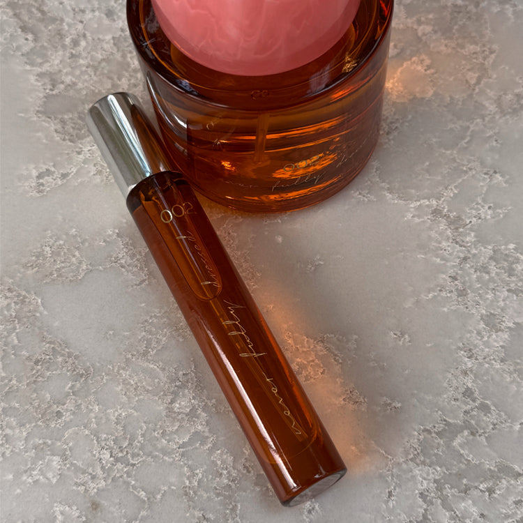 NFD Eau De Parfum 002 10ml travel spritz in amber glass with a silver cap, resting on a speckled stone surface.