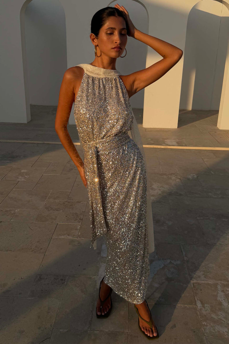 Gonna Jaspre maxi a portafoglio in paillettes argento, indossata come abito halter multi-wear in un set architettonico.