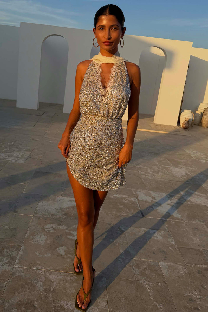 Mini gonna Jaspre a portafoglio in paillettes argento con dischi metallici su una modella all'aperto alla golden hour.