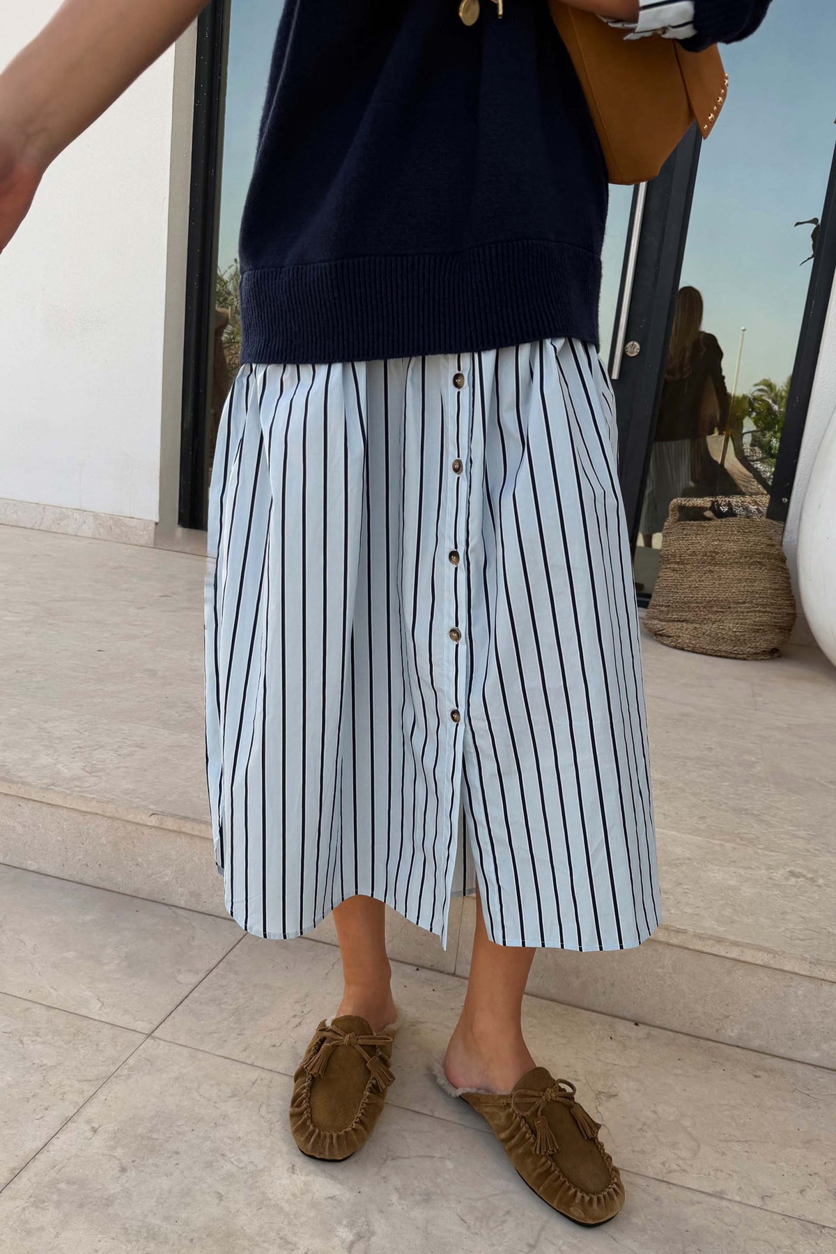 Navy knit jumper dress with a blue striped cotton midaxi skirt and buttons, styled with brown loafers for London looks.