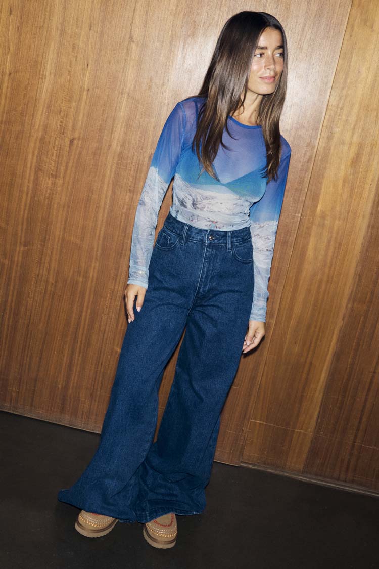 Blue Ski Slopes Mesh Long Sleeve Top with a sheer mountain print, paired with dark wash wide-leg denim jeans.