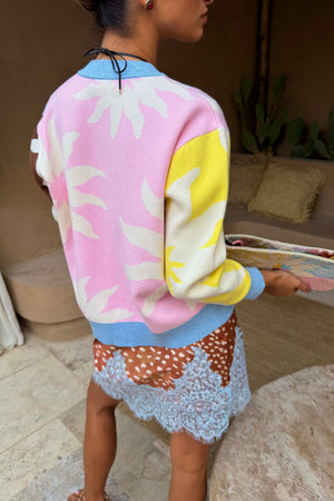 Cardigan Soleil Hollie rosa e giallo con motivi a sole, visto dal retro su modella alta 162 cm in taglia S.
