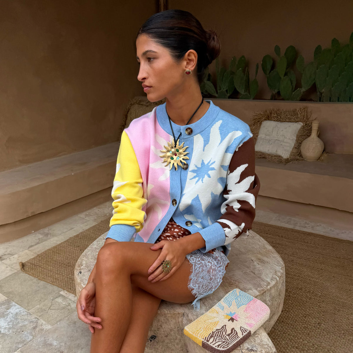 Cardigan Soleil Hollie in maglia multicolore con motivi a sole, indossato in un ambiente rustico all'aperto.