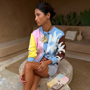 Cardigan Soleil Hollie in maglia multicolore con motivi a sole, indossato in un ambiente rustico all'aperto.