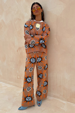 Modella con maglione Tan Sun Copenhagen e pantaloni coordinati marroni con stampa a soli.