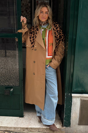 Tan Trench Coat with gold studs and leopard scarf, a statement staple styled over a green knit and wide-leg jeans.