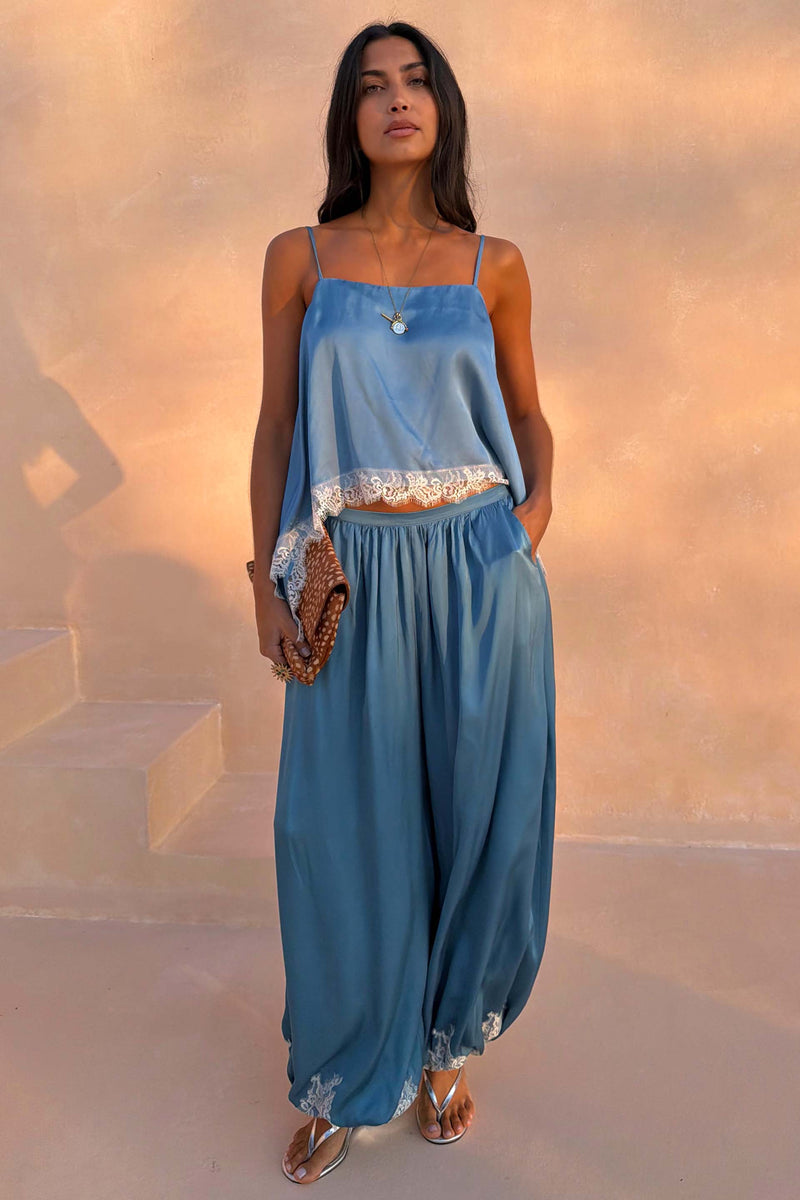 Modella con pantaloni a palloncino Blue Lace in raso blu e top coordinato con pizzo.
