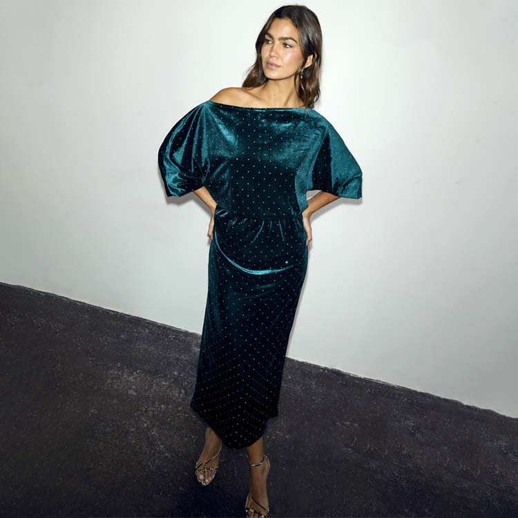 Emerald Velvet Tilly Dress with an off-shoulder neckline, voluminous top and sparkling detail on a model.