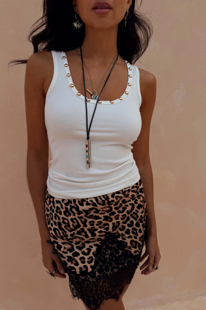 White ribbed vest with gold stud detailing along the neckline, styled with a leopard print lace skirt.
