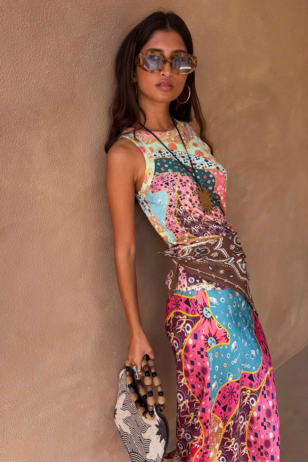 Occhiali da sole Yellow Tort Wiggle Arm tartarugati indossati con un abito colorato a fantasia.
