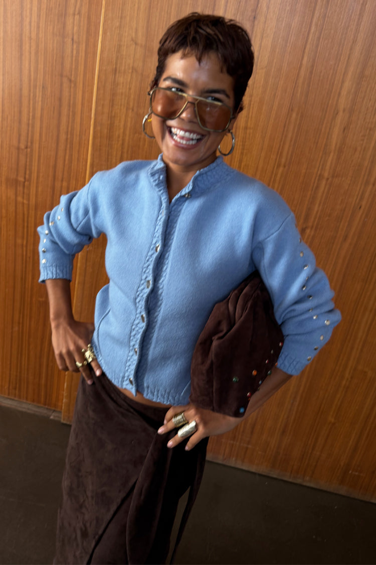 Ice Blue Studded Cardigan with silver metal sleeve studs, styled with a dark brown skirt and clutch bag.