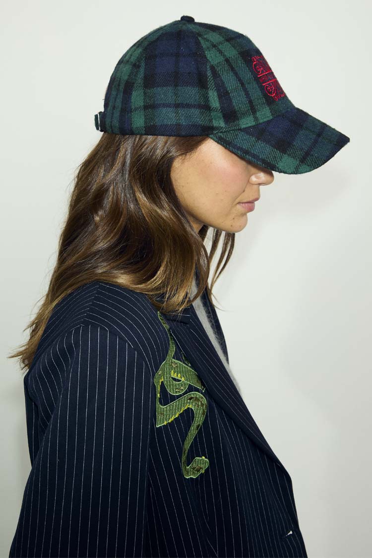 Navy and green tartan cap with red NFD logo embroidery, worn with a pinstripe blazer with snake detail.